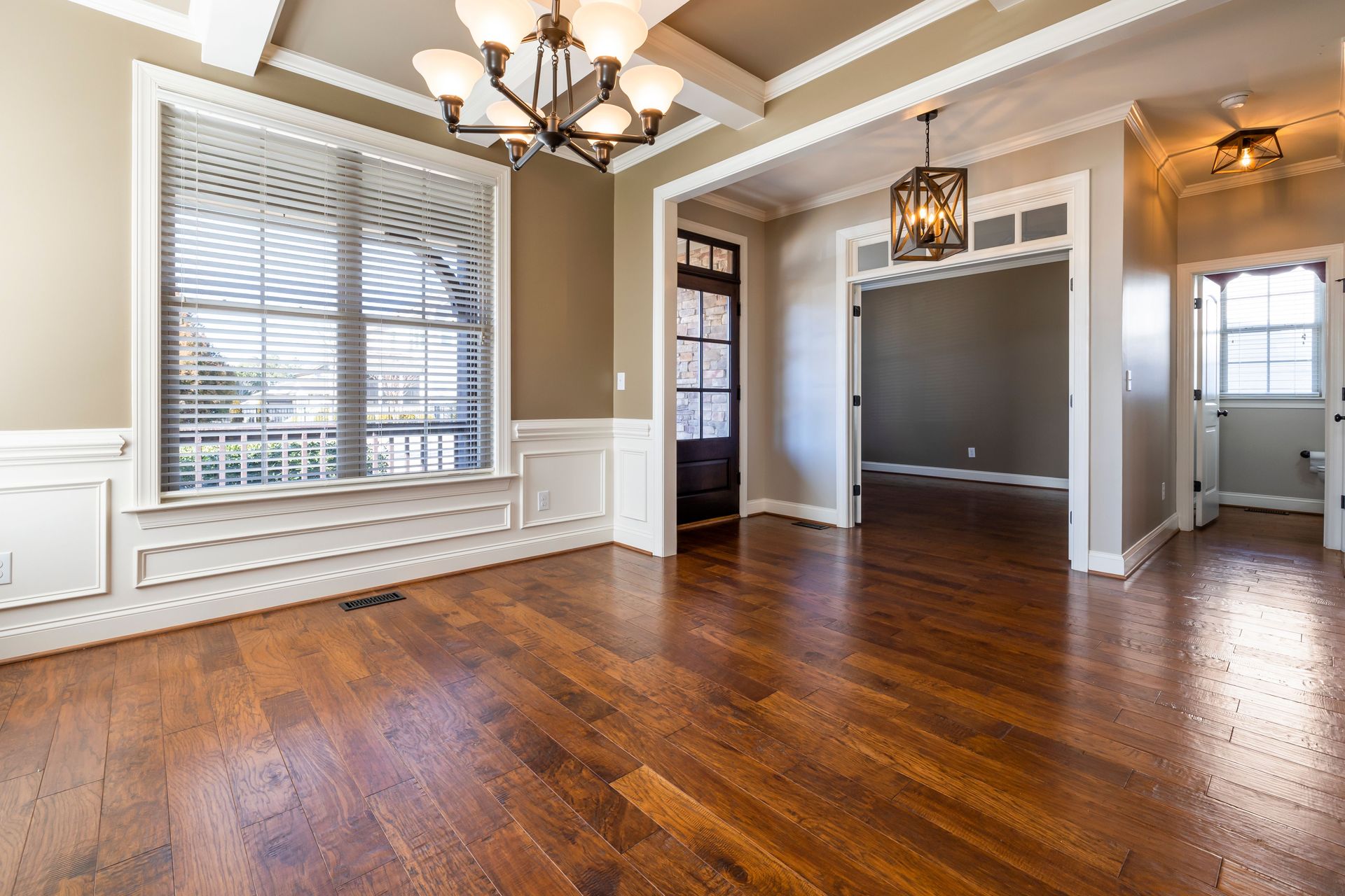 Elegant room with wooden flooring, chandelier, and natural lighting.