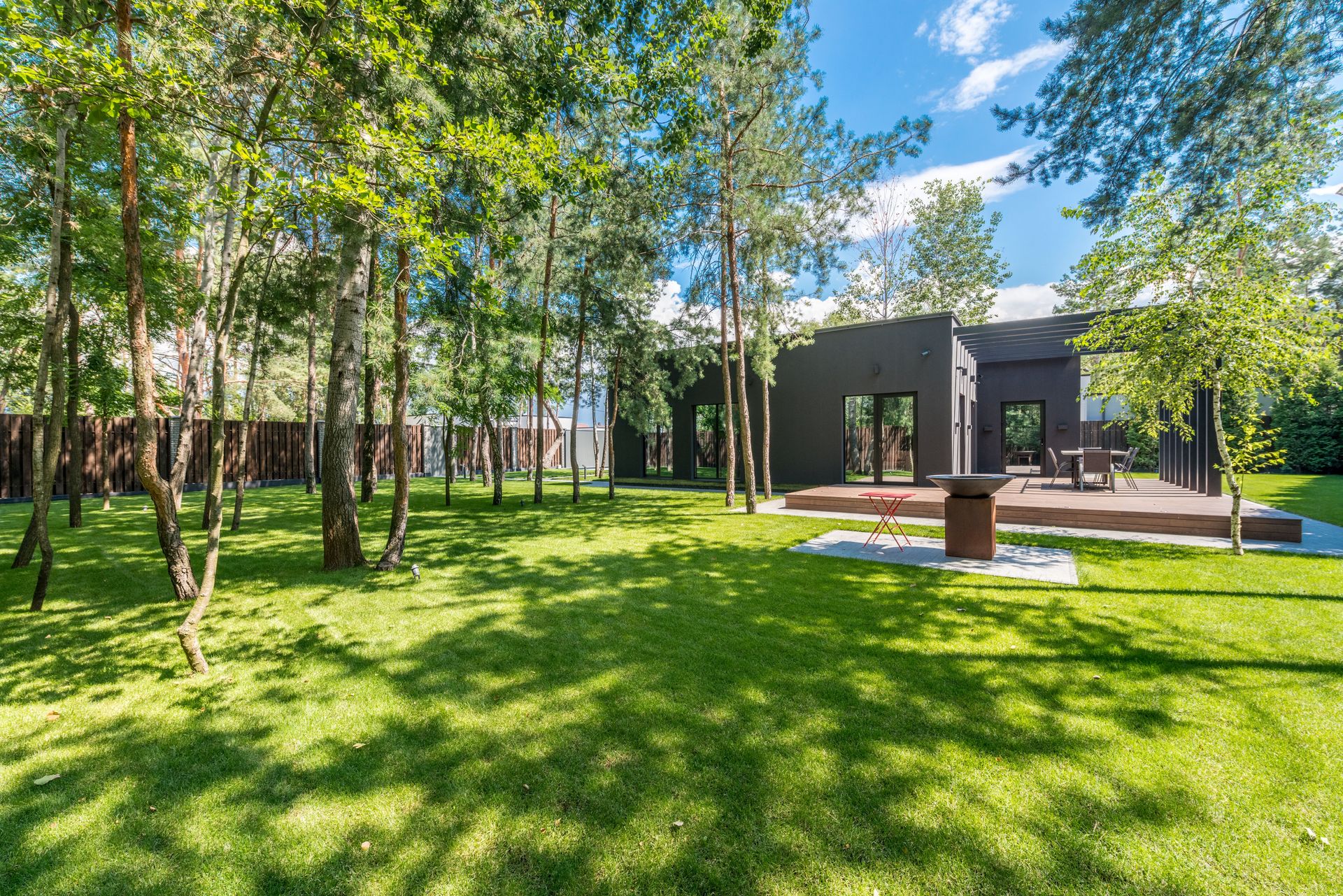 Contemporary home surrounded by trees and vibrant lawn.